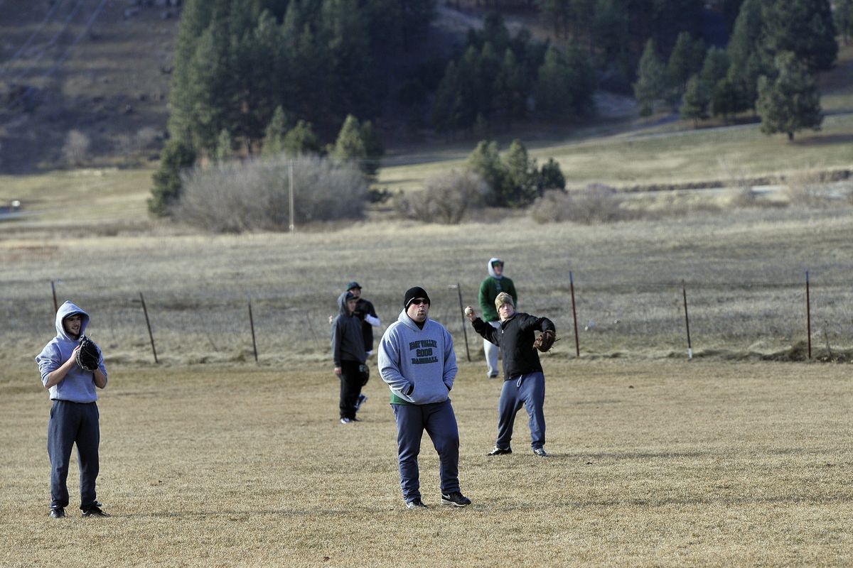 Bundled against the wind, players and coaches from the East Valley Knights play catch at the start of practice Tuesday at the school. Spring sports teams have had few chances to hold practices outside.
