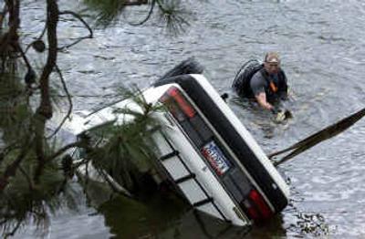 
Kootenai County sheriff's Deputy Eric Hildebrandt watches as the Mazda is pulled out of Fernan Lake on Thursday morning following Wednesday's crash.
 (Jesse Tinsley / The Spokesman-Review)