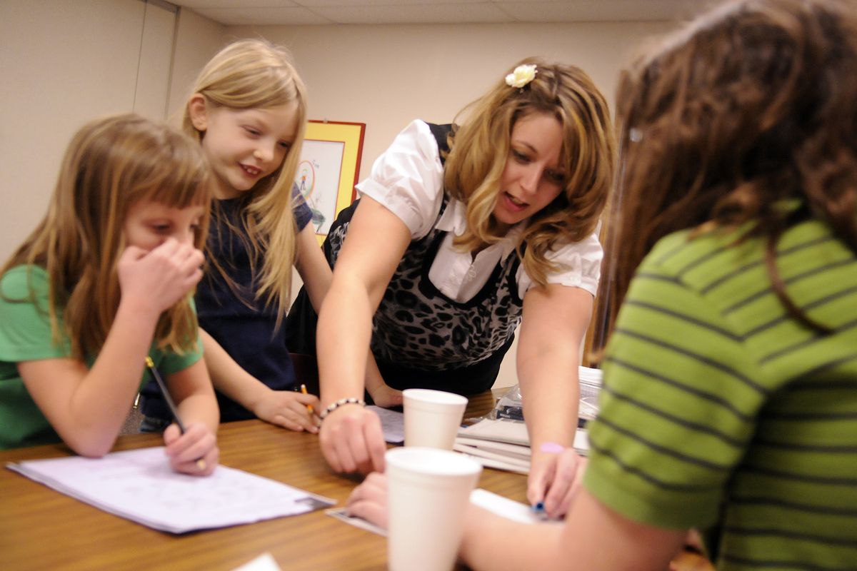 Christ Lutheran Church has hired certified teacher Holly Moro to assist in Homework Helpers, an after-school program. Here, she helps Summit sixth-grader Lauren Walker (back to camera) with a math problem as first-graders Kate Walker, left, and Taylor Looker watch. (J. Bart Rayniak)