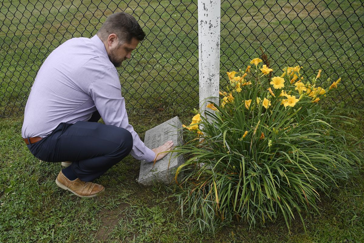 Brett Eagleson, son of 9/11 victim Bruce Eagleson, wipes grass off a memorial stone for his father at the baseball field where his father used to coach on Friday in Middletown, Conn.  (Jessica Hill)