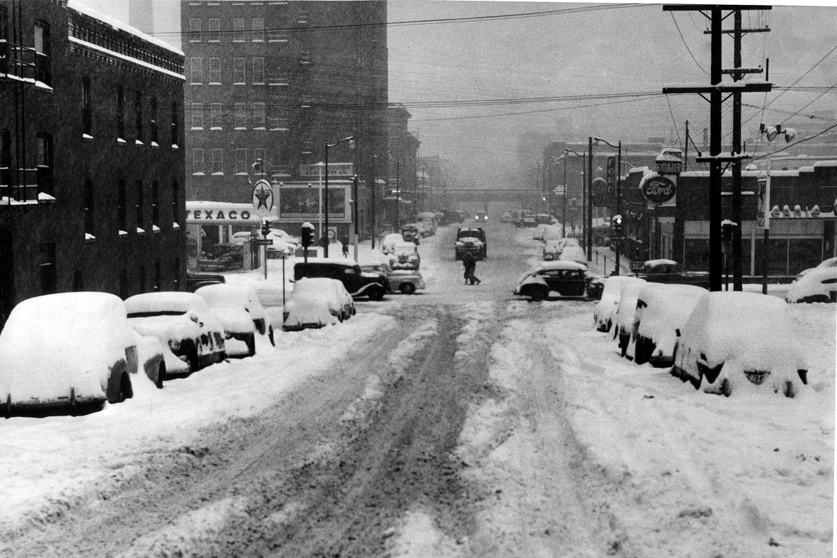 Snow-covered streets and cars make travel difficult in December 1951.  This photo was taken on Post Street looking north between Fourth and Third streets. (Photo Archive / The Spokesman-Review)