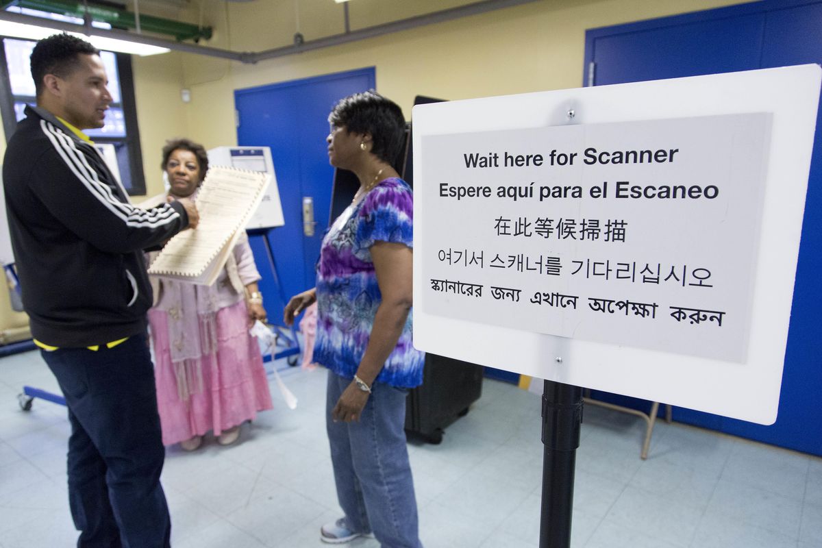 Darling Diaz, left, talks with poll worker Jamie Williams-Rivera before voting in the Flushing neighborhood in the Queens borough of New York, Tuesday, April 19, 2016. The sign includes instructions in English, Spanish, Chinese, Korean and Bengali. Diaz is originally from the Dominican Republic. (Mark Lennihan / Associated Press)