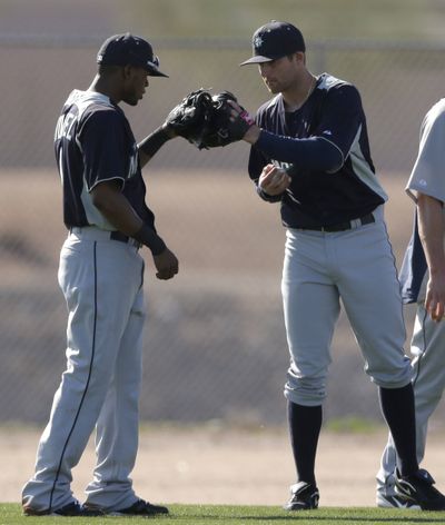 Shortstops Carlos Triunfel, left, and Brad Miller bump gloves after a participating in a drill. (Associated Press)