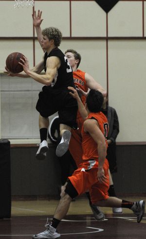 Whitworth's Dustin McConnell makes a pass from in the key as Lewis and Clark's Quentin Sims (in back) and Ben Neves defend Friday night in the Second half at Whitworth University. (Colin Mulvany / The Spokesman-Review)