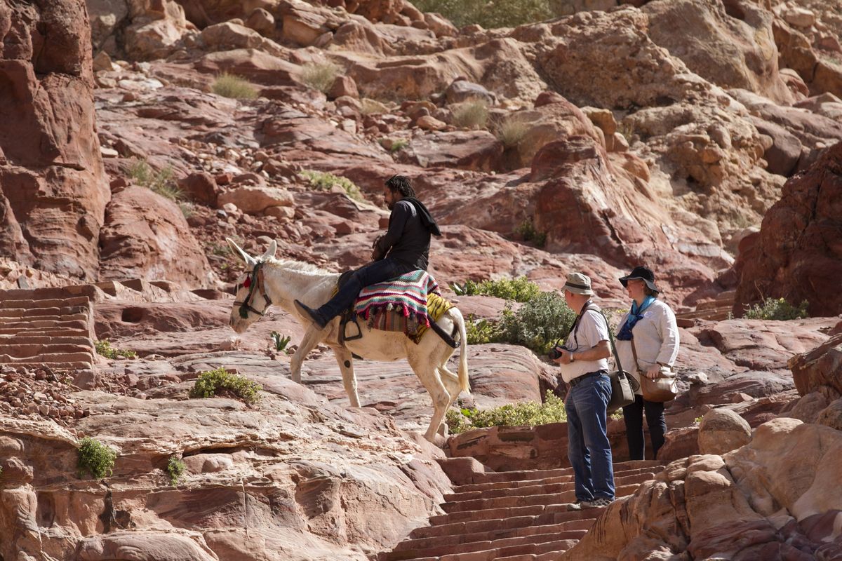 At left: Tourists look at a man riding a donkey in the ancient city of Petra, Jordan. (Associated Press)