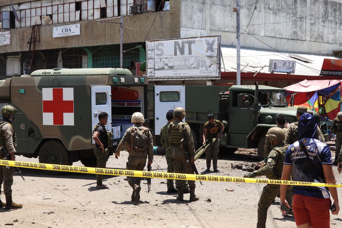EDS NOTE: GRAPHIC CONTENT - Soldiers retrieve bodies at a site of an explosion in the town of Jolo, Sulu province, southern Philippines, Monday Aug. 24, 2020. Bombs exploded in a southern Philippine town Monday, killing several soldiers and wounding other military personnel and civilians despite extra tight security due to threats from Abu Sayyaf militants. (NICKEE BUTLANGAN)