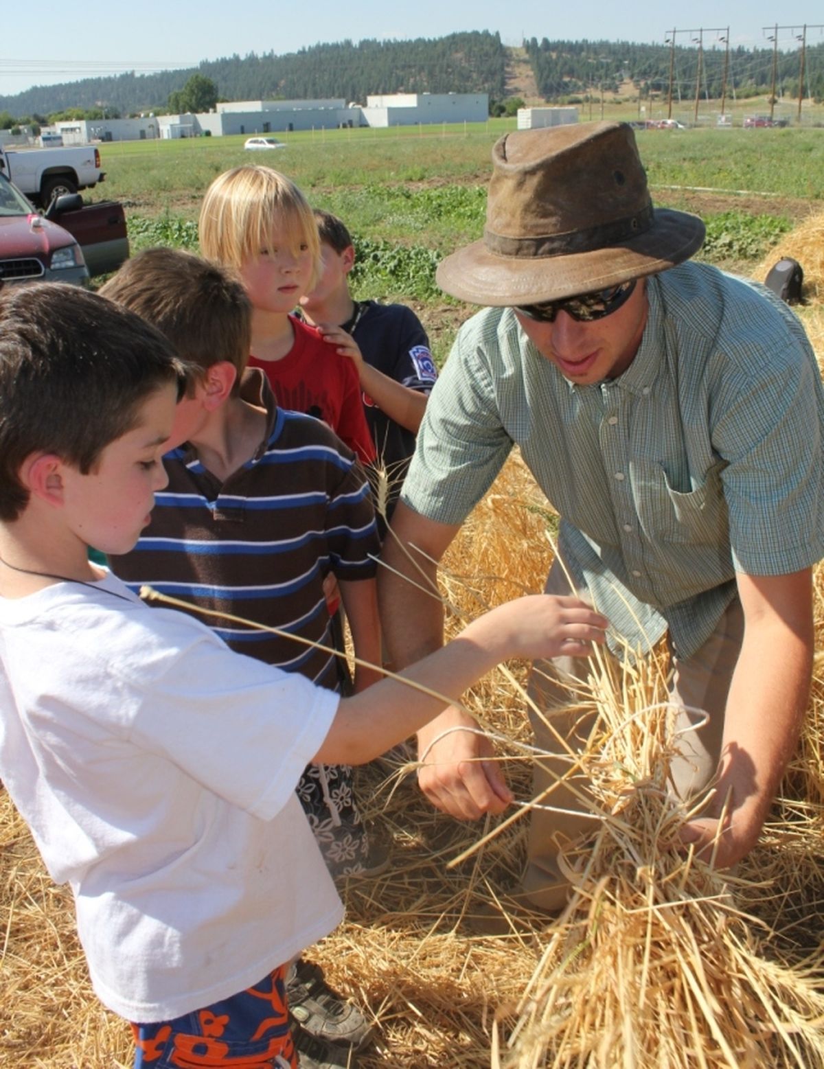 John Conley helps his students tie a bunch of wheat. (Sandra Hoskings / Down to Earth NW Correspondenr)