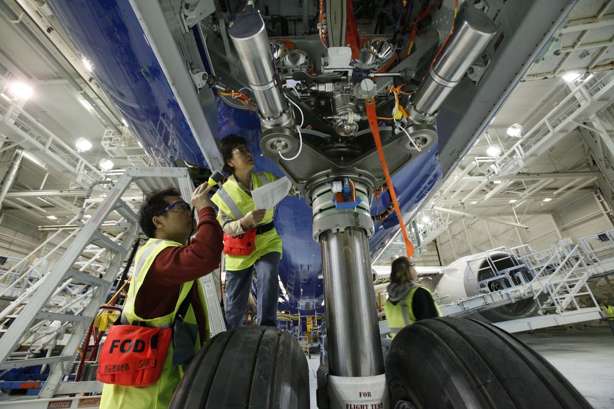 Boeing workers look into the well for the front landing gear on a 787 at the plant in Everett. (Associated Press)