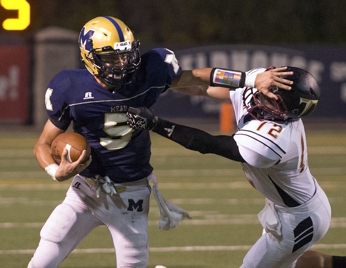Mead quarterback Matt Wetzel, left, stiff-arms University defensive back Jeff Beaty in first half. (Colin Mulvany)
