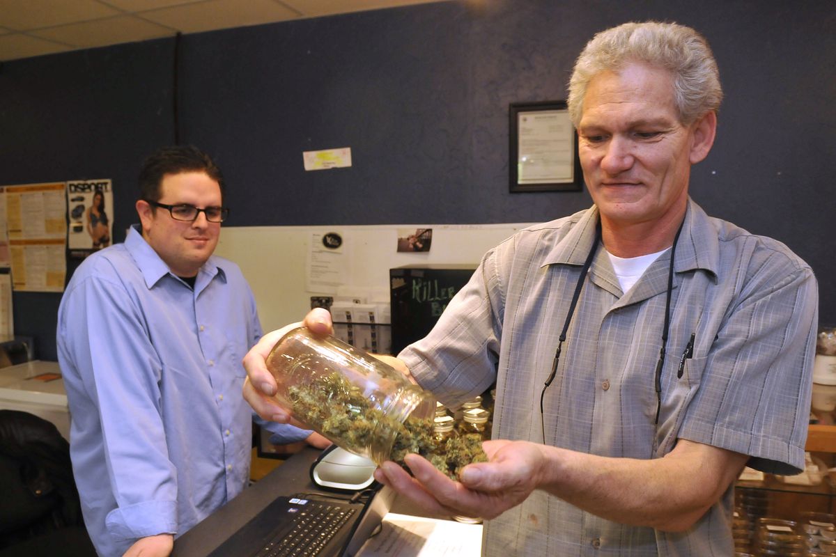 Herbal Connection Club owner Paul Lugo, right, examines some of his inventory of marijuana. He distributes to patients who show a doctor’s prescription at his storefront in the Garland District. At left is Robert Metzger, a volunteer and patient of the dispensary. Metzger is a Navy veteran who was severely injured in the service and also has Parkinson’s disease. (Jesse Tinsley)