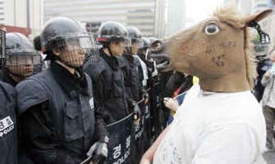 
A South Korean protester wearing a horse mask stands face to face with riot police.
 (The Spokesman-Review)