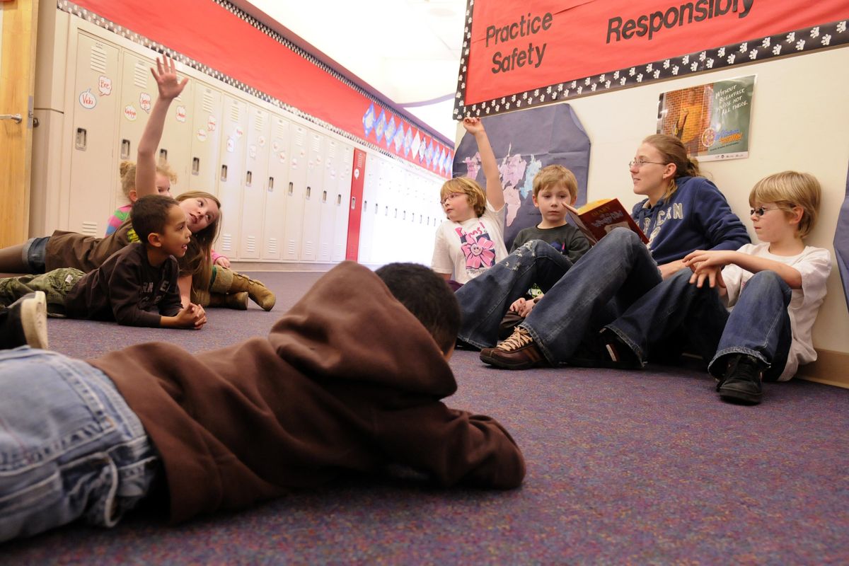 Dawn Halmai, a youth leader for the YMCA, reads during Kids Cafe time in the hallway of Trent Elementary School on Jan. 20. Second Harvest Food Bank, in conjunction with the YMCA, has opened eight Kids Cafes in Spokane Valley schools to provide nutritious snacks  to 150 children in the program. (J. BART RAYNIAK)