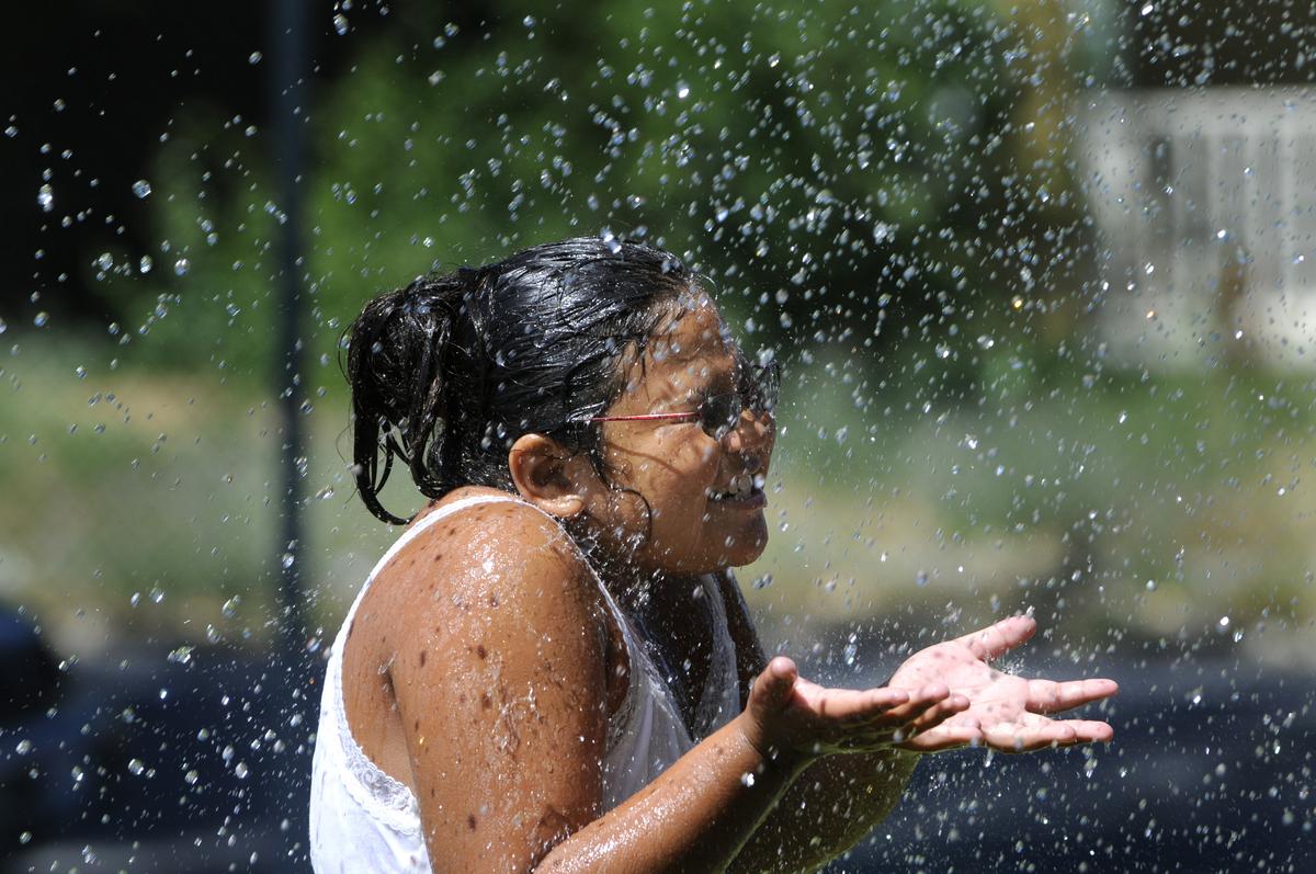 Jazmin Ramirez, 9, gets doused by a sprinkler during field events at the Indian Youth Summer Program at Havermale High School on Thursday. The program blends learning and playtime. (Jesse Tinsley / The Spokesman-Review)
