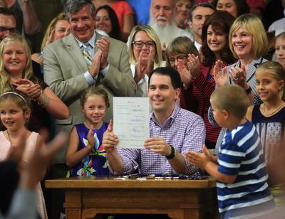 Wisconsin Gov. Scott Walker displays a signed 2015-17 state budget Sunday during a ceremony on the production floor of Valveworks USA in Waukesha, Wis. (Associated Press)