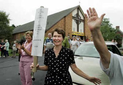 
Sheila Pecoraro, a parishioner at St. Albert the Great church in Weymouth, Mass., behind, holds a placard and waves along with others at fellow parishioners departing the church by bus. Three bus loads of parishioners traveled to Boston hoping to convince a judge that they, and not the archdiocese, own the church and reverse the Boston Archdiocese's decision to close the parish. 
 (Associated Press / The Spokesman-Review)