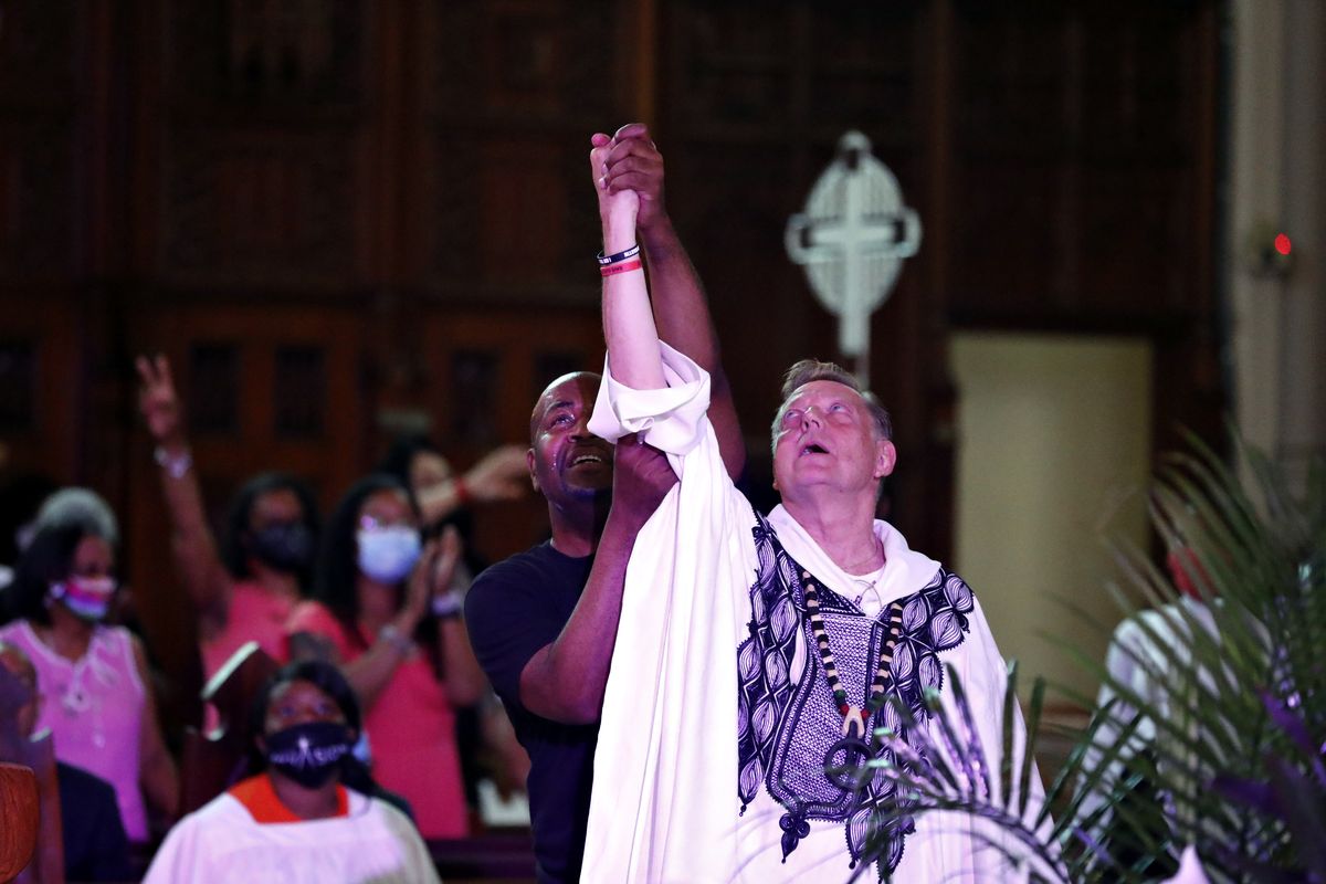 A parishioner raises Rev. Michael Pfleger’s arm as he conducts his first Sunday church service as a senior pastor at St. Sabina Catholic Church following his reinstatement by Archdiocese of Chicago after decades-old sexual abuse allegations against minors on Sunday in the Auburn Gresham neighborhood in Chicago.  (Shafkat Anowar)