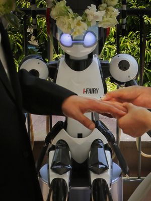 I-Fairy, a four-foot tall seated robot with flashing eyes and plastic pigtails, wearing a wreath of flowers, directs a wedding ceremony for groom Tomohiro Shibata, 42, and bride Satoko Inouye, 36, at a Tokyo restaurant Sunday, May 16, 2010. The wedding was the first time a marriage had been led by a robot, according to manufacturer Kokoro Co. (Itsuo Inouye / Associated Press)