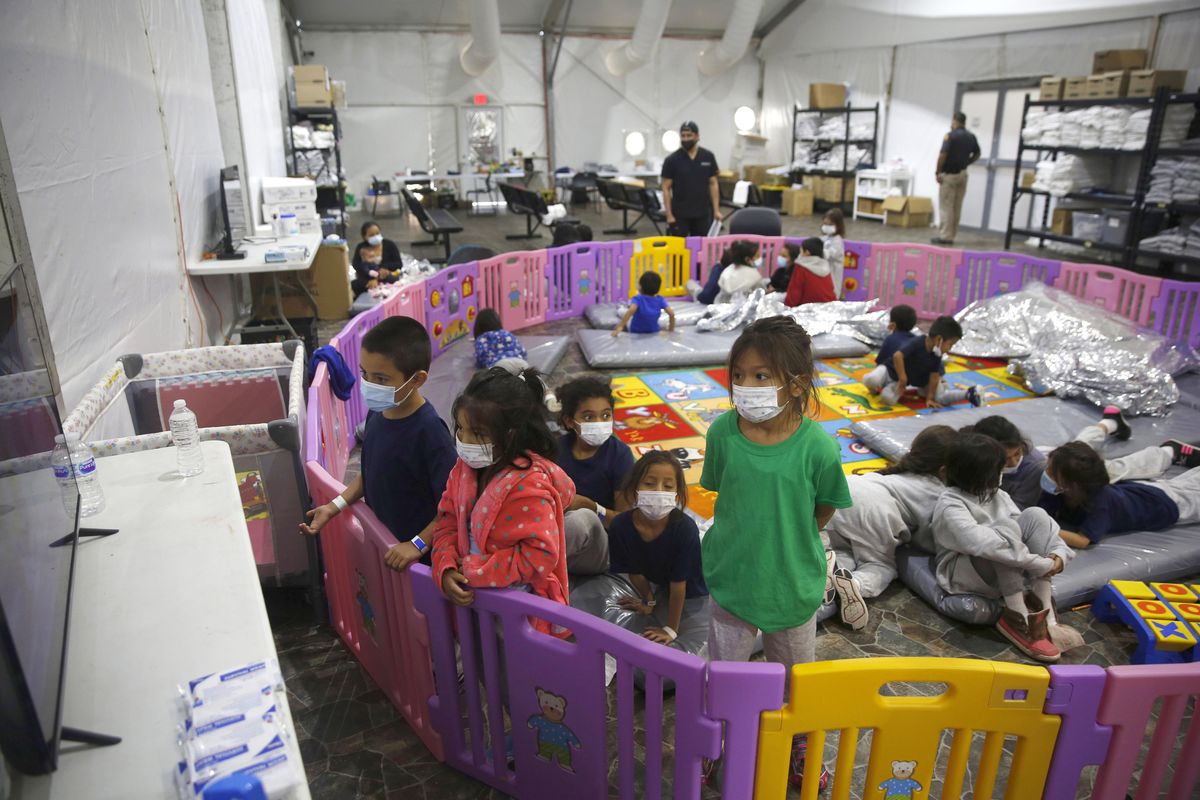 FILE – In this March 30, 2021, file photo, young unaccompanied migrants, from ages 3 to 9, watch television inside a playpen at the U.S. Customs and Border Protection facility, the main detention center for unaccompanied children in the Rio Grande Valley, in Donna, Texas. For the third time in seven years, U.S. officials are scrambling to handle a dramatic spike in children crossing the U.S.-Mexico border alone, leading to a massive expansion in emergency facilities to house them as more kids arrive than are being released to close relatives in the United States.  (Dario Lopez-Mills)