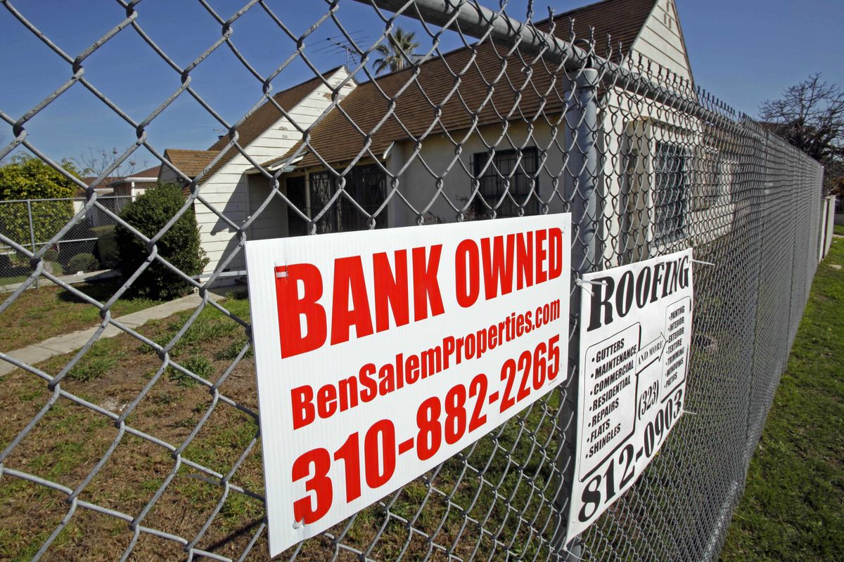 A vacant home surrounded by a chain link fence carrying a “bank owned” sign and ads from local tradespeople is seen in Los Angeles this week. Housing analysts forecast that more than 2 million borrowers may lose their homes this year.