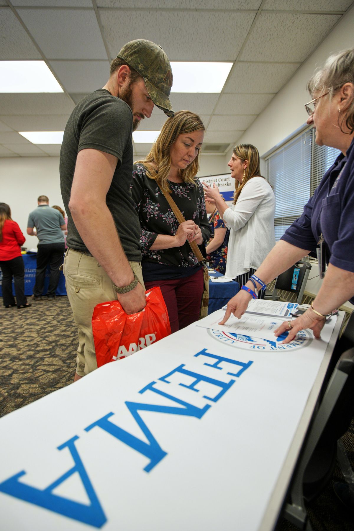 In this April 25, 2019, photo, April Kleinschmit and her husband, Brandon, talk to FEMA representative Kristina Pooler, right, about available FEMA jobs, at a job fair in Lincoln, Neb. With federal disaster recovery staffers scrambling to meet needs amid floods, hurricanes and fires, they are now dealing with another issue – historically low unemployment that