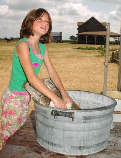 
Kristen Personius looks up  as she tries her hand at washing clothes the homestead way  at the Ingalls Homestead near De Smet, S.D.
 (The Spokesman-Review)