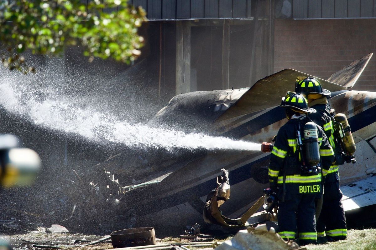 Firefighters spray water at the scene of a plane crash, in Farmington, Conn., Thursday. Sept. 2, 2021. All four people aboard a small jet were killed Thursday morning when it crashed shortly after taking off from Robertson Airport before crashing into the building at Trumpf Inc., a manufacturing company, Farmington Police Lt. Tim McKenzie said.  (Mark Mirko)