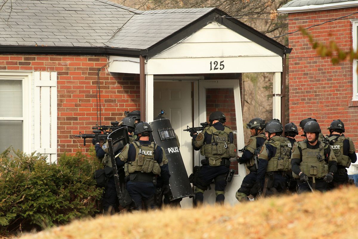 A police tactical team prepares to enter a home on Dade Avenue, in Ferguson, Mo., on Thursday in search of a suspect they believed to be in the attic. Police were investigating the shooting of two police officers during protests early Thursday morning. Several people were taken in for questioning but later were released and no arrests were made. (Associated Press)