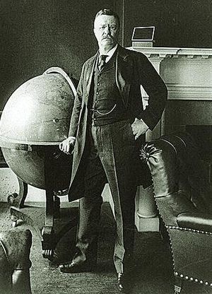 Theodore Roosevelt, an avid traveler, stands next to a large globe. (Wikimedia Commons)