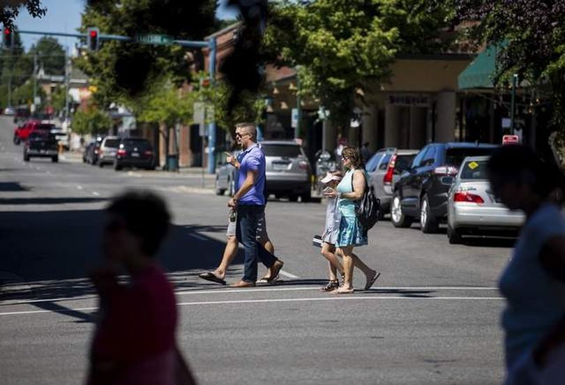 Pedestrians cross Fourth Street on Sherman Avenue last week. Downtown walkers' use of buttons to change traffic signals affects their motoring counterparts' driving experience by turning lights from green to red. (Loren Benoit/Coeur d'Alene Press photo)