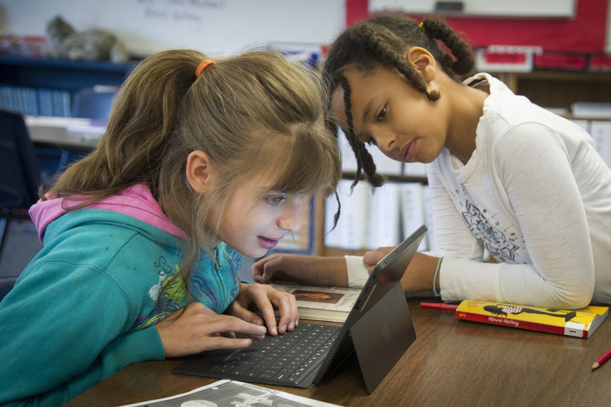 Saint George’s fifth-graders Erika Piotrowski, left, and Zadie Rigsby use a Microsoft Surface tablet while working together on a science fair project about the top 10 diseases of 1912. The school is in the process of integrating tablet computers into its curriculum. (Colin Mulvany)