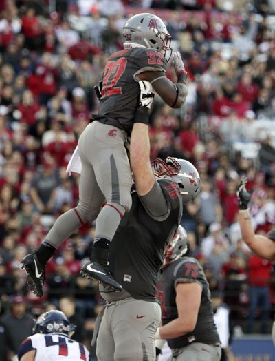 Washington State offensive lineman Cody O'Connell picks up running back James Williams after Williams ran for a touchdown during the second half of the game against Arizona in Pullman on Nov. 5. O’Connell was named a unanimouse All-American on Wednesday, the first WSU player since kicker Jason Hanson. (Young Kwak / AP)
