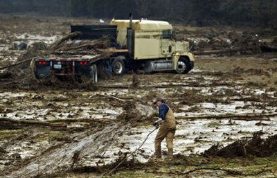 
Tow truck driver Kerry Buckley drags a cable out to a truck that was washed off a highway near the Black River on Wednesday in Lestervile, Mo. 
 (Associated Press / The Spokesman-Review)