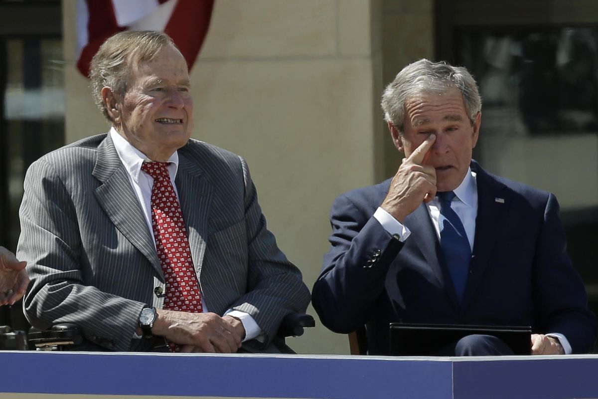 Former president George W. Bush wipes a tear after his speech during the dedication of the George W. Bush Presidential Center Thursday in Dallas. Former president George H.W. Bush is at left. (David J. Phillip / AP)