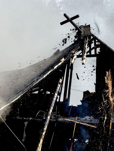 A cross made of steel breaks loose as crews continued to battle the arson blaze at St. Ann's Catholic Church in Bonners Ferry on Thursday, April 21, 2016. (Kathy Plonka / The Spokesman-Review)