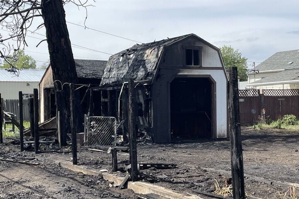 A garage, fence and large pine tree were some of the items that burned in a fire Wednesday in north Spokane. (Garrett Cabeza / The Spokesman-Review)
