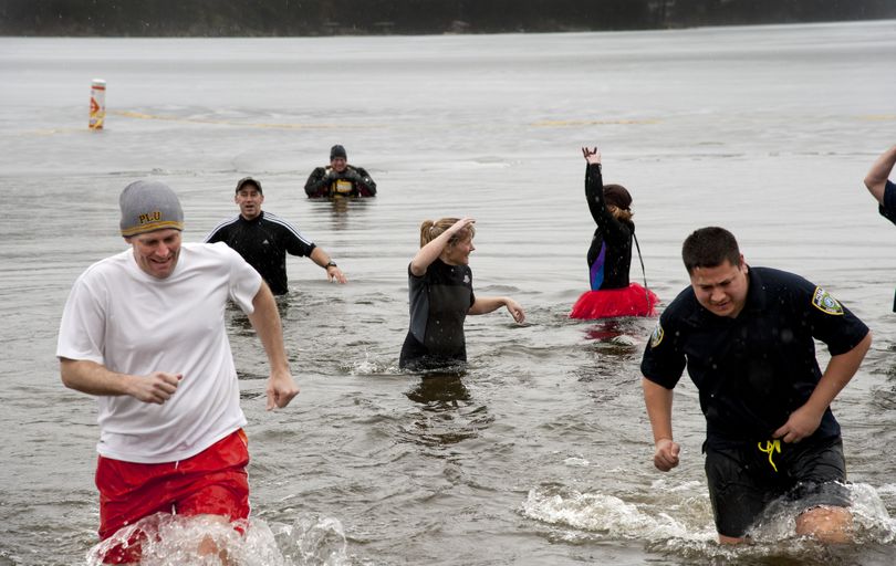 Washington State Patrol trooper Jon McKee, left, and Airway Heights police officer Mike Suniga haul their cold bodies out of Liberty Lake on Feb. 22 after taking their 16th polar plunge of the day in support of Special Olympics Washington. (Dan Pelle)