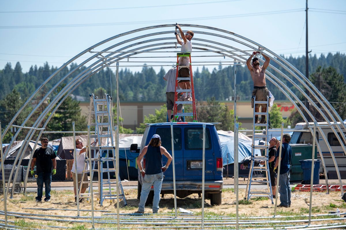 Volunteers assemble a quonset-style tent across the street from Camp Hope in the East Central area north of Interstate 90, where hundreds of people live in tents on Department of Transportation land. The tent is intended to be a cooling shelter when temperatures rise this week.  (Jesse Tinsley/THE SPOKESMAN-REVIEW)