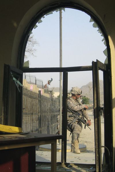 A U.S. soldier is seen through a window at the scene of a suicide attack in Torkham,   Afghanistan, on Sunday  that killed a border police officer and a civilian. (Associated Press / The Spokesman-Review)