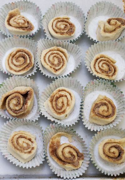 Mini cinnamon rolls rise in cupcake papers before baking.
