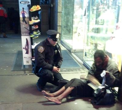 New York City police Officer Larry DePrimo presents a barefoot homeless man in New York’s Times Square with socks and all-weather boots. (Associated Press)