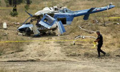 
Deputy Larry Humphreys moves police tape at the crash site of a Bonneville Power Administration helicopter Tuesday. Pilot John J. Cooley, 57, of Cheney, was killed. 
 (Kathryn Stevens / The Spokesman-Review)