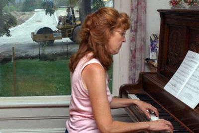 
Mary Pollard plays the piano in her living room while construction crews work on the street in front of her home in Greenacres on Thursday. The street outside her home used to be on the same level as her yard but now sits a couple feet higher, a design that will send stormwater from the new road directly into her yard. 
 (Liz Kishimoto / The Spokesman-Review)