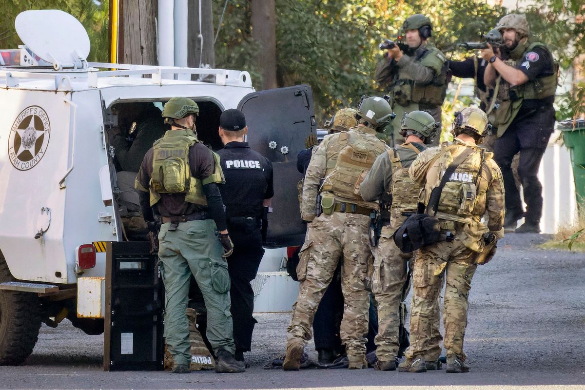 Law enforcement officers prepare to fire tear gas rounds at an apartment during a standoff with a man after shots were fired in the 100 block of South Almon Street on Tuesday in Moscow, Idaho. The officers were in the alley behind the apartment.  (Geoff Crimmins/For the Spokesm-Review)