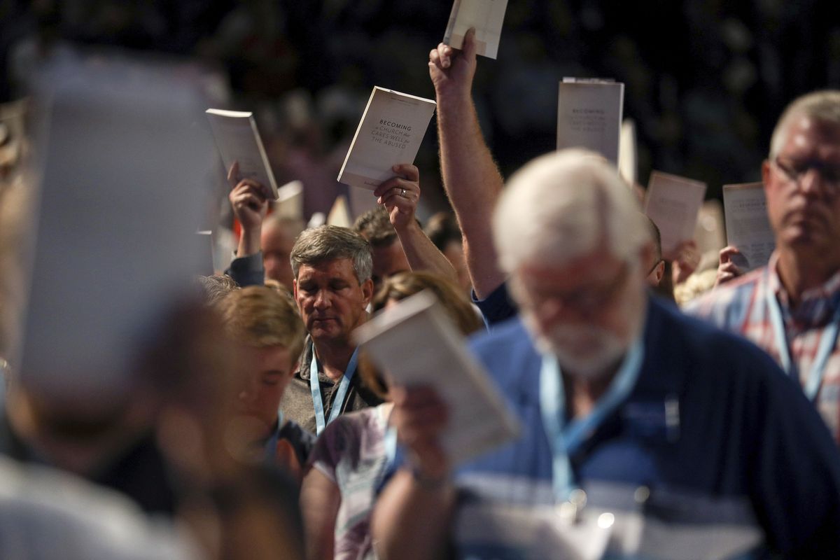 In this Wednesday, June 12, 2019 photo, Bill Golden, and thousands of others, hold up copies of a training handbook related to sexual abuse within Southern Baptist churches during a speech by SBC President J. D. Greear on the second day of the SBC