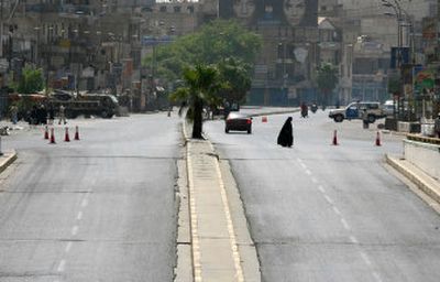 
A woman crosses a deserted street Friday just before the prayer-day vehicle ban in Baghdad.
 (Associated Press / The Spokesman-Review)