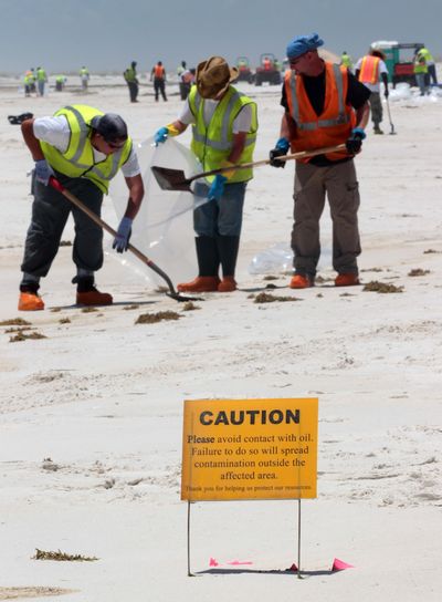 Oil cleanup workers outnumber tourists on the beach in Pensacola Beach, Fla., on Wednesday after oil washed ashore overnight, leaving an ugly stain.  (Associated Press)