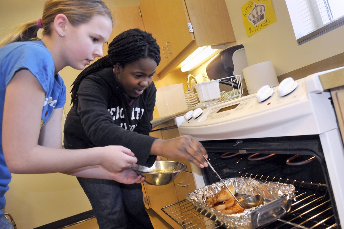 Jenna Adams, 11, and Jorden Glanville, 12, baste pieces of chicken with barbecue sauce Wednesday.
