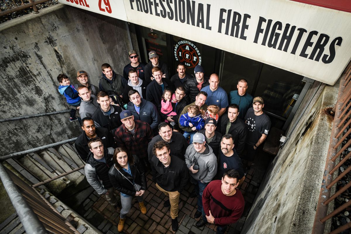 These Spokane firefighters and others are at risk of being laid off if Proposition 1, a new property tax levy voters will weigh in on in February, does not pass. Back row, left to right: Alex Peltram (wearing sunglasses), Sean Doyle, Seth Clark, Ben Olberding, Jeff Hanson, Jeremy Heimbigner, Conrad Richie. Second row – Jesse Schmidlkofer (black jacket), Russell Theodorson, Joel Chavez, Kristopher Blair, Chris Rogers, Derek Phillips. Middle row: Aaron Peterson (holding young child), Dan Anderson, Nick Ulowetz, Jeff Brown, Philippe Moore, Devon Gustafson, Devin Haefer, Matt Shroeder, Andrew Johnson. Front row: Kevin Goodloe (black jacket), Connor Reding, McCalle Feller, Sean Champoux and Gilmar DeAmorim. (Colin Mulvany / The Spokesman-Review)