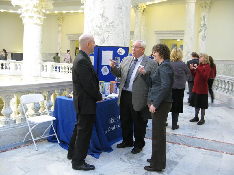 Sen. Lee Heider, R-Twin Falls, talks with Idaho Council for the Deaf and Hard of Hearing executive director Steven Snow, left, with the help of a sign language interpreter, right. The council held a legislative breakfast in the Statehouse rotunda on Thursday, with displays from groups that serve the deaf and hard of hearing. (Betsy Russell)