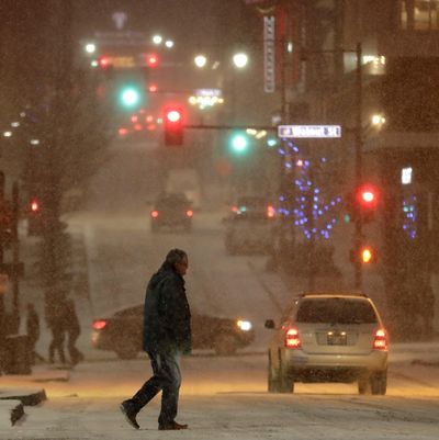 A pedestrian walks across a street in downtown Kansas City, Mo., on Saturday, Dec. 17, 2016. A winter storm of snow, freezing rain and bone-chilling temperatures hit the nation’s mid-section and East Coast over the weekend. (Charlie Riedel / AP)